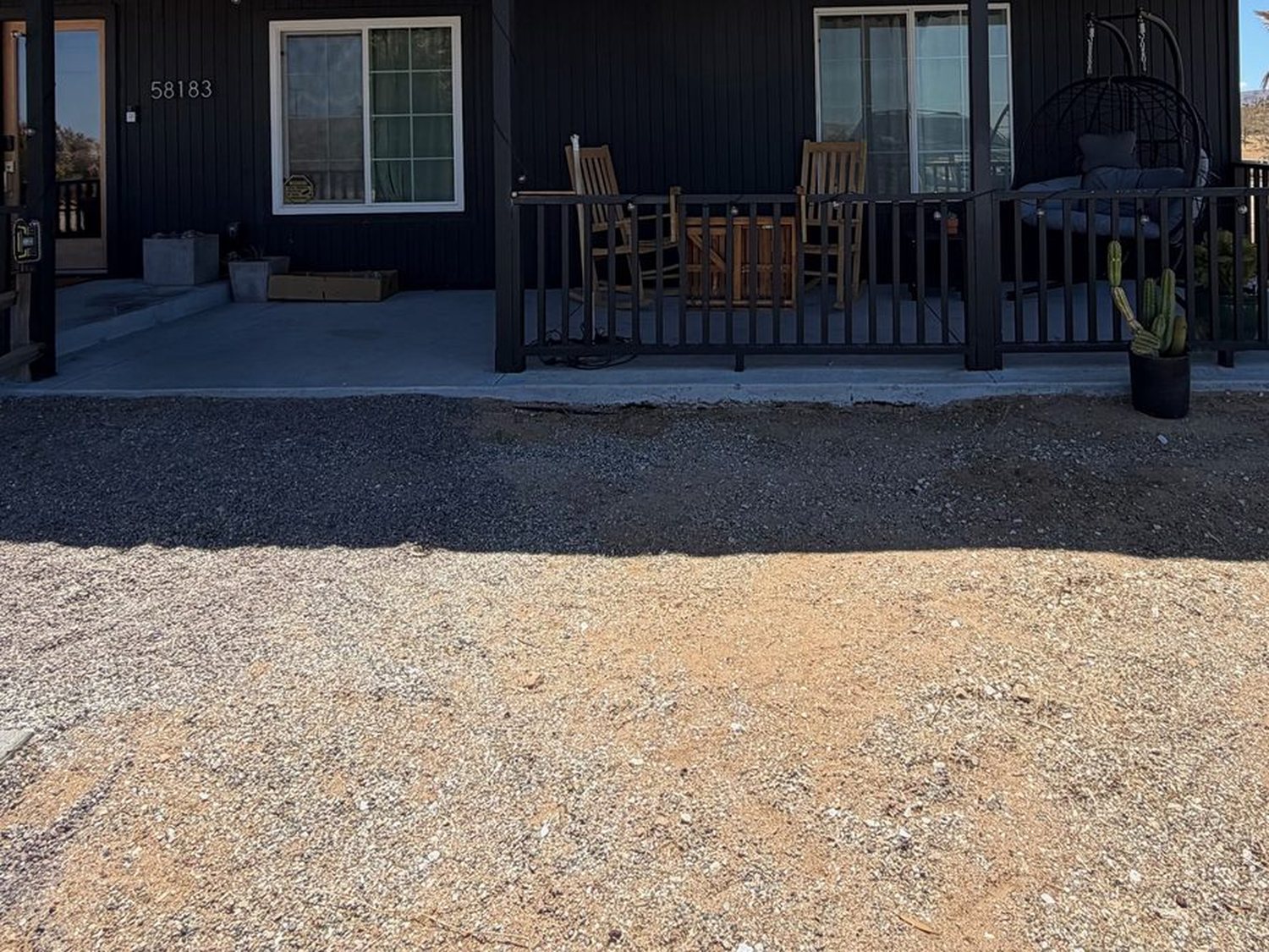 Entrance before, a bare covered porch with gravel and no planting