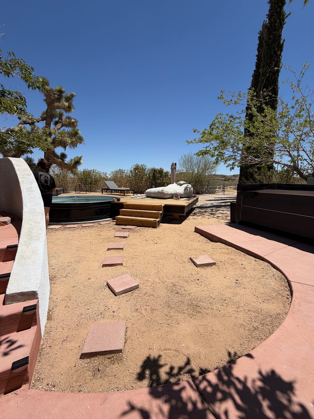 Hot tub area before, a stock tank pool on bare ground with scattered pavers