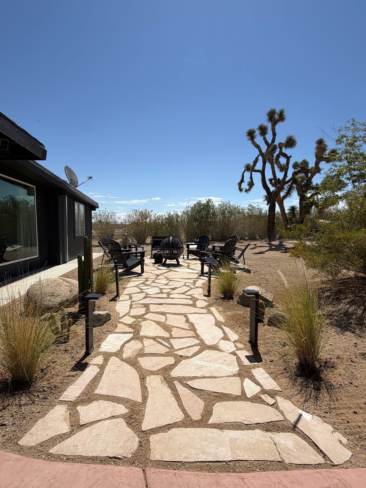Seating area after, a flagstone patio with a fire pit, chairs, and native grasses