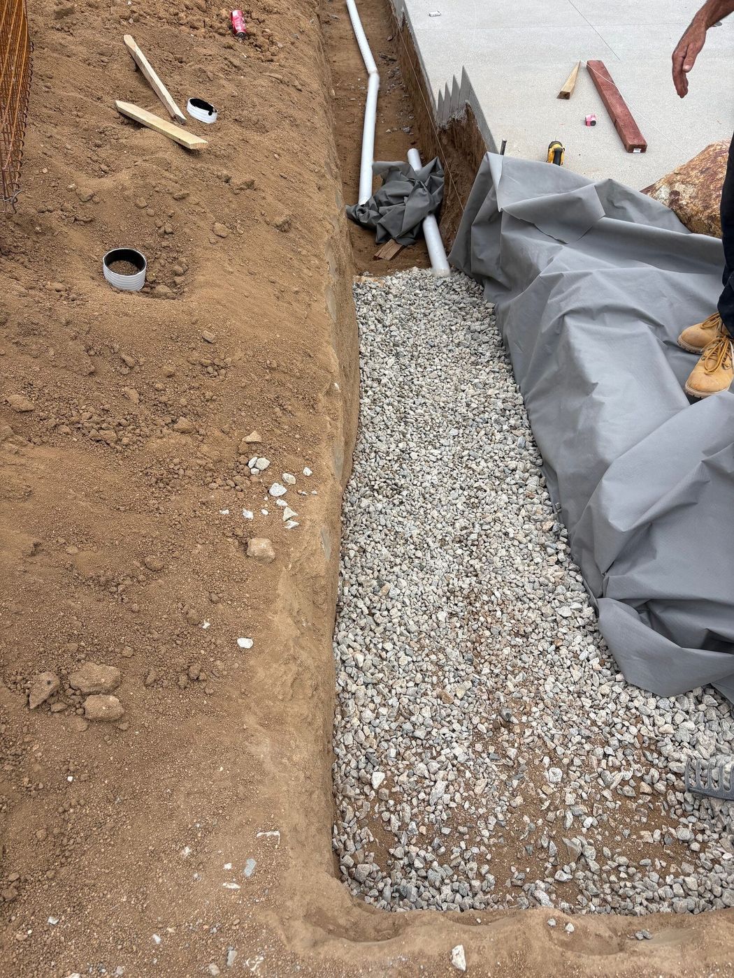 Geotextile fabric, gravel base, and perforated drain pipe along the trench