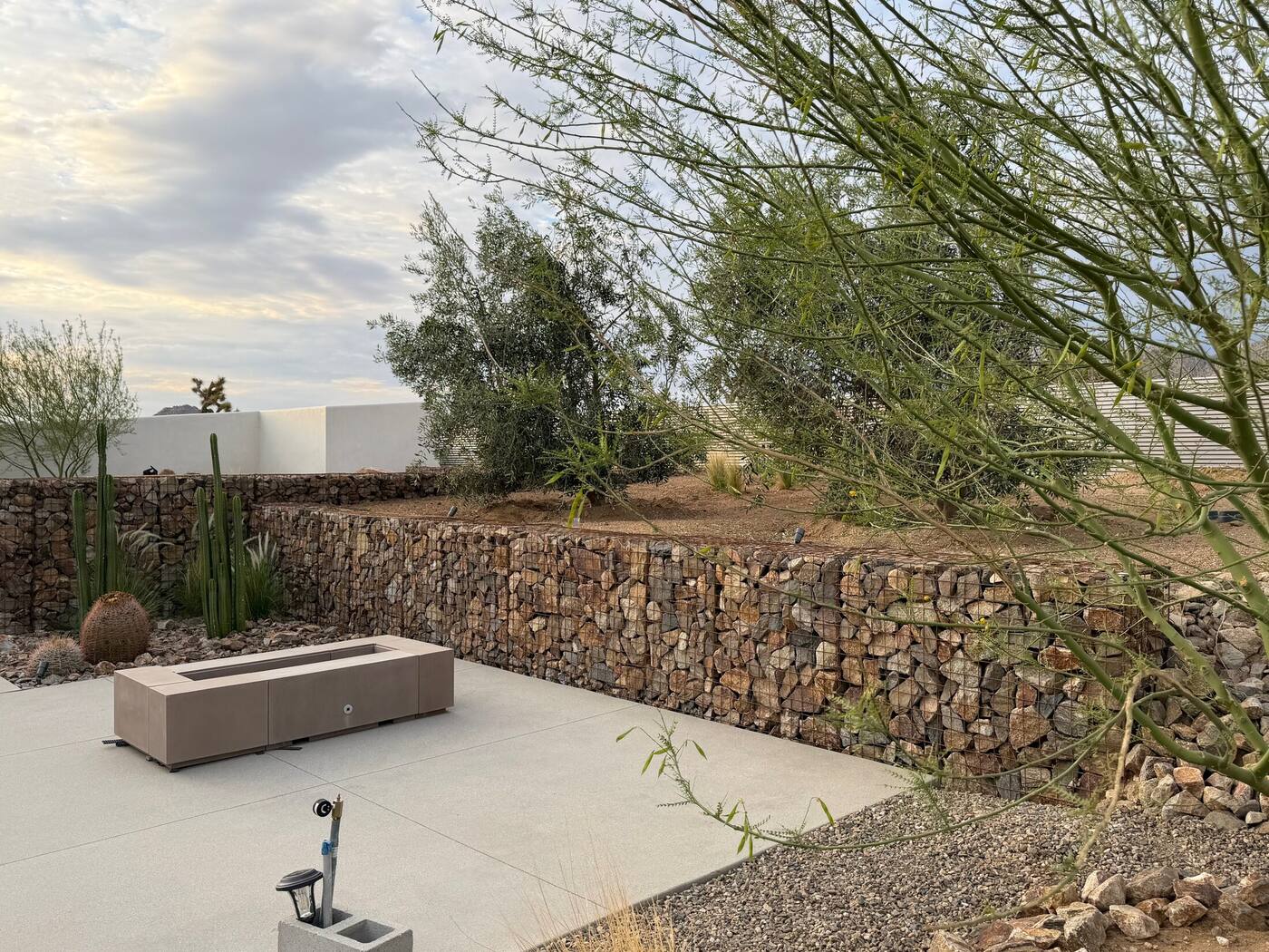 Wide view of the finished backyard with gabion walls framing the pool and patio