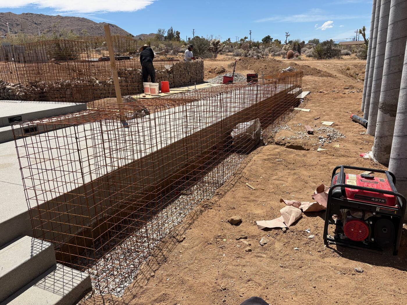 Crew tying and assembling a gabion cage section by hand