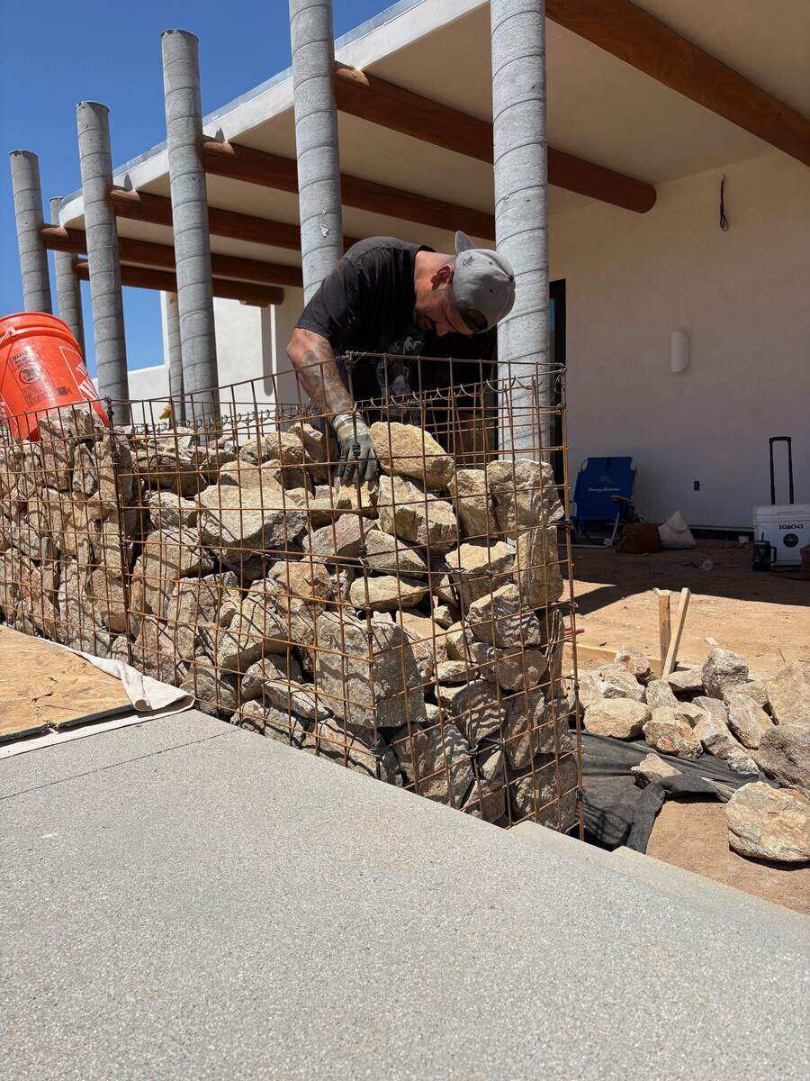 Crew member hand-placing a stone into a gabion cage