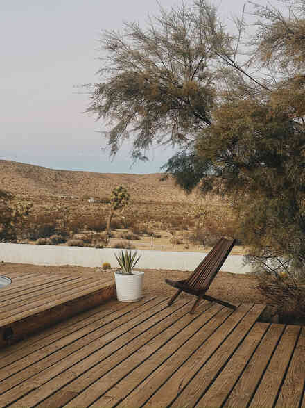 Wood deck lounge chair overlooking Joshua tree hillside views