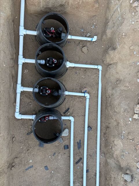 Four irrigation zone valves manifolded together in a trench